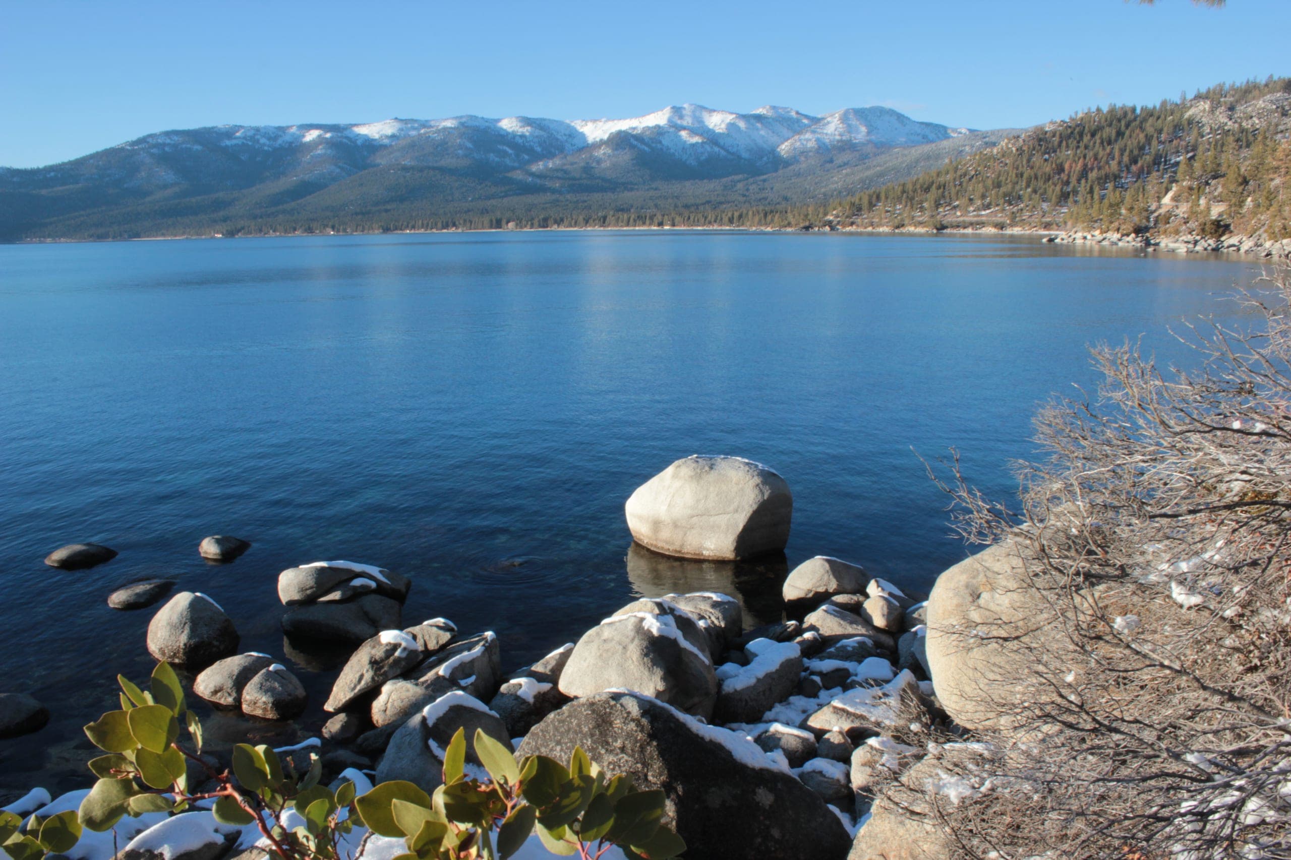 Lake Tahoe ringed by snow-covered Sierra peaks under a clear winter sky